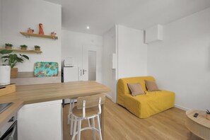 Eine moderne Küche mit Holzarbeitsplatten, einem weißen Stuhl, einem gelben Sofa und einem kleinen Esstisch.