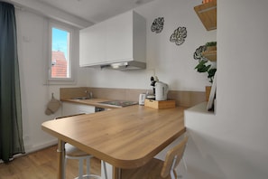 Une cuisine moderne avec un plan de travail en bois, des armoires blanches, une cuisinière intégrée et une fenêtre donnant sur des immeubles.