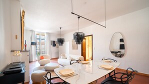 Uma sala de jantar moderna com uma mesa branca, cadeiras pretas e um espelho grande na parede.