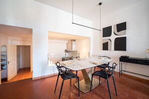 Eine moderne Küche mit weißen Schränken, einem Esstisch für vier Personen und einem schwarzen abstrakten Gemälde an der Wand.