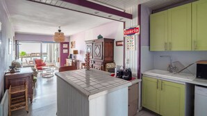 A kitchen with a tiled island, green cabinets, and a hanging light fixture. - Escale à Canet - Au bord de la plage (Canet-en-Roussillon)