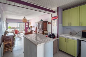 A kitchen with a tiled island, green cabinets, and a hanging light fixture. - Escale à Canet - Au bord de la plage (Canet-en-Roussillon)