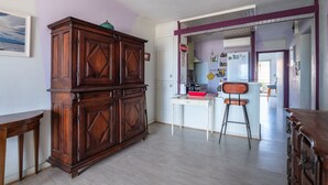 A kitchen with a wooden cabinet, a white table, and a bar stool. - Escale à Canet - Au bord de la plage (Canet-en-Roussillon)