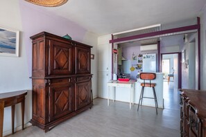 A kitchen with a wooden cabinet, a white table, and a bar stool. - Escale à Canet - Au bord de la plage (Canet-en-Roussillon)