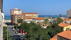 Ein mehrstöckiges Gebäude an der Küste mit freiem Blick auf das Meer und einer Straße mit parkenden Autos.