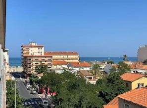 A coastal building with multiple floors, a clear view of the sea, and a street with parked cars. - Le Studio de Canet - À 200 m de la plage (Canet-en-Roussillon)