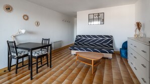 Ein Zimmer mit Esstisch, Stühlen, einer Couch, einem kleinen Holztisch, einem Schminktisch und Wanddekorationen.
