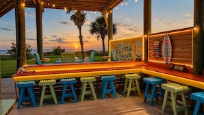 Un bar à thème balnéaire, doté d’une structure en bois, de places assises en plein air et d’un panneau indiquant les règles à respecter sur la plage.
