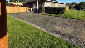 Ein eingeschossiges Haus mit Kiesweg, Rasen und Holzzaun.