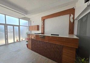 A reception desk with a 'RECEPTION' sign, a wooden counter, and a large window with a view. - Townhouse IIM Lucknow Formerly Lexa Grand (Lucknow)