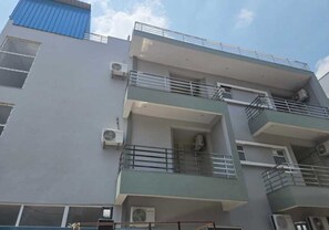 A multi-story building with balconies, air conditioning units, and a blue roof. - Townhouse IIM Lucknow Formerly Lexa Grand (Lucknow)