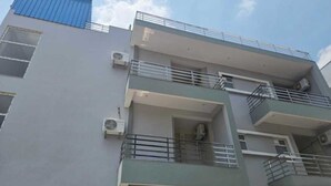A multi-story building with balconies, air conditioning units, and a blue roof. - Deluxe Lexa Grand (Lucknow)