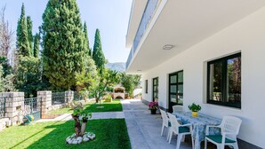 Ein modernes Gebäude mit Terrasse, Außenmöbeln und einem gepflegten Garten.