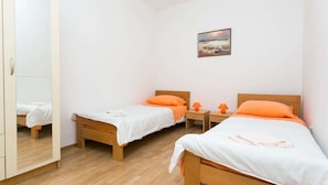 Ein Schlafzimmer mit zwei Betten, Holzboden, einem Kleiderschrank und einem Bild an der Wand.