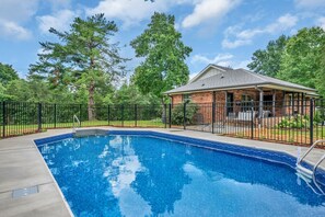 A swimming pool with a brick house and a covered patio area. - Evergreen Cottage Escape (Pegram)