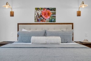 A bedroom with a large bed, two wall-mounted lamps, and a framed picture above the bed. - Evergreen Cottage Escape (Pegram)