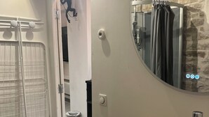 Un bagno con un lavandino bianco, uno specchio, un asciugamano, una tenda da doccia e un portascopevoli.
