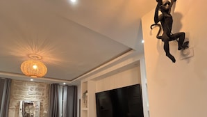 Un soggiorno moderno con televisore a schermo piatto, una parete decorata in pietra, un lampadario, un divano e un elemento decorativo a parete.