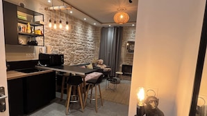 Una cucina moderna con zona pranzo, parete in pietra e un originale lampadario.