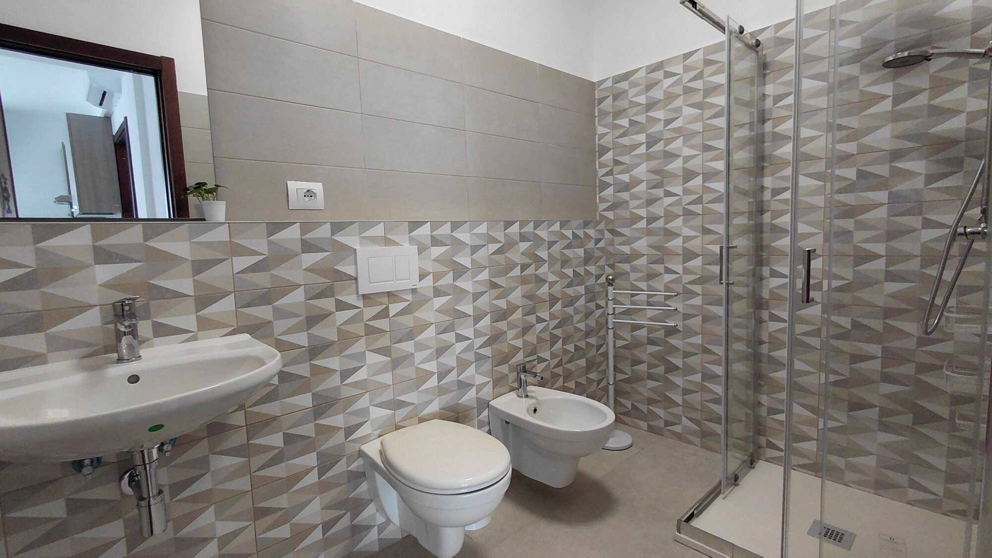 A bathroom with a shower, toilet, bidet, and sink.