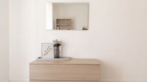 A minimalist room with a wooden dresser, a framed artwork, and a vase with flowers. - Urban Nest Alghero - Two Bedroom Apartment, Sleeps 5 (Alghero)