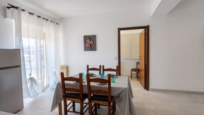 Een eethoek met een tafel voor vier personen, een koelkast en uitzicht op een balkon.