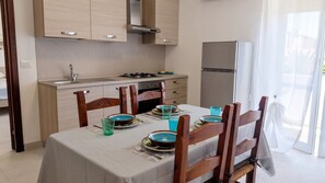 Eine moderne Küche mit Holzschränken, einem Essplatz komplett mit Tellern und Gläsern, und einem Kühlschrank.