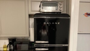 Una cuina amb un frigorífic negre, un microones i un forn elèctric.