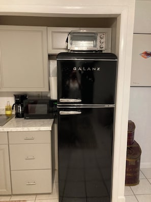 Uma cozinha com geladeira preta, micro-ondas e forno elétrico.