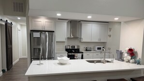 A modern kitchen with a central island, stainless steel appliances, and a bar stool seating area.