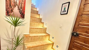Eine Treppe mit integrierter Beleuchtung, einem Blumentopf, einem gerahmten Bild und einer Holztür.