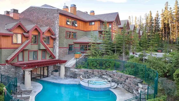 Un grand bâtiment doté d’une piscine et d’un jacuzzi, entouré d’arbres.