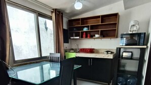 Eine kleine Küche mit Esstisch, Stühlen, Deckenventilator und Fenster.
