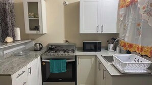 Una cocina compacta con estufa a gas, horno, microondas y fregadero.