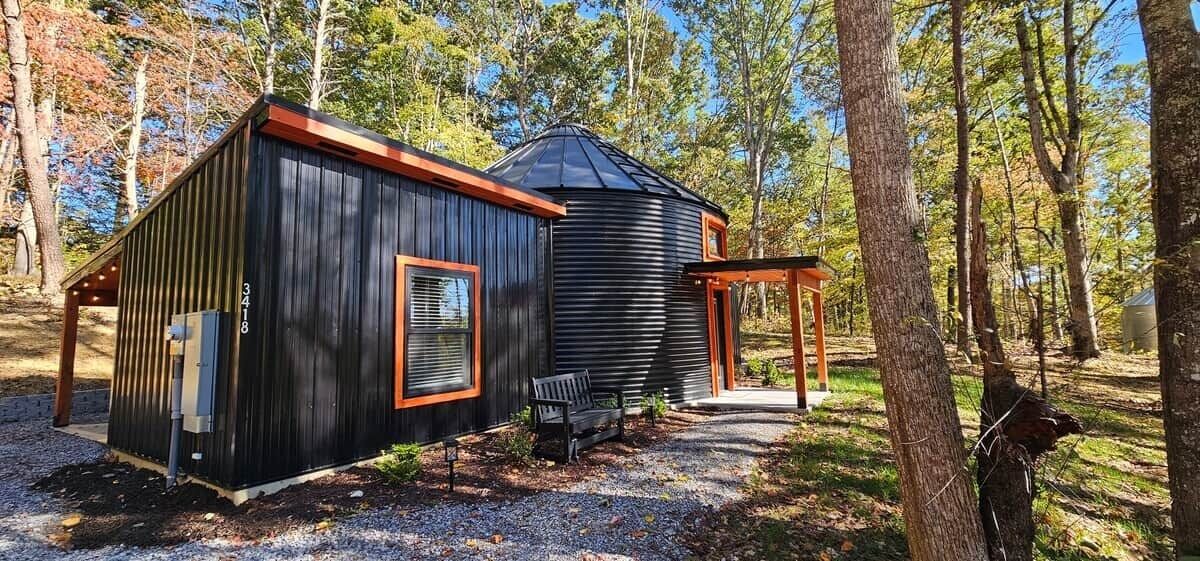A cabin with a covered porch and a separate building with a sloped roof.