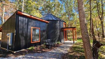 A cabin with a covered porch and a separate building with a sloped roof.