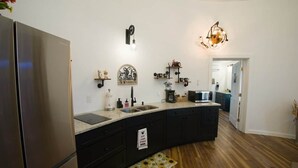 A modern kitchen with a stainless steel refrigerator, a built-in sink, and a large island with a countertop. - Silo Retreat (Sevierville)