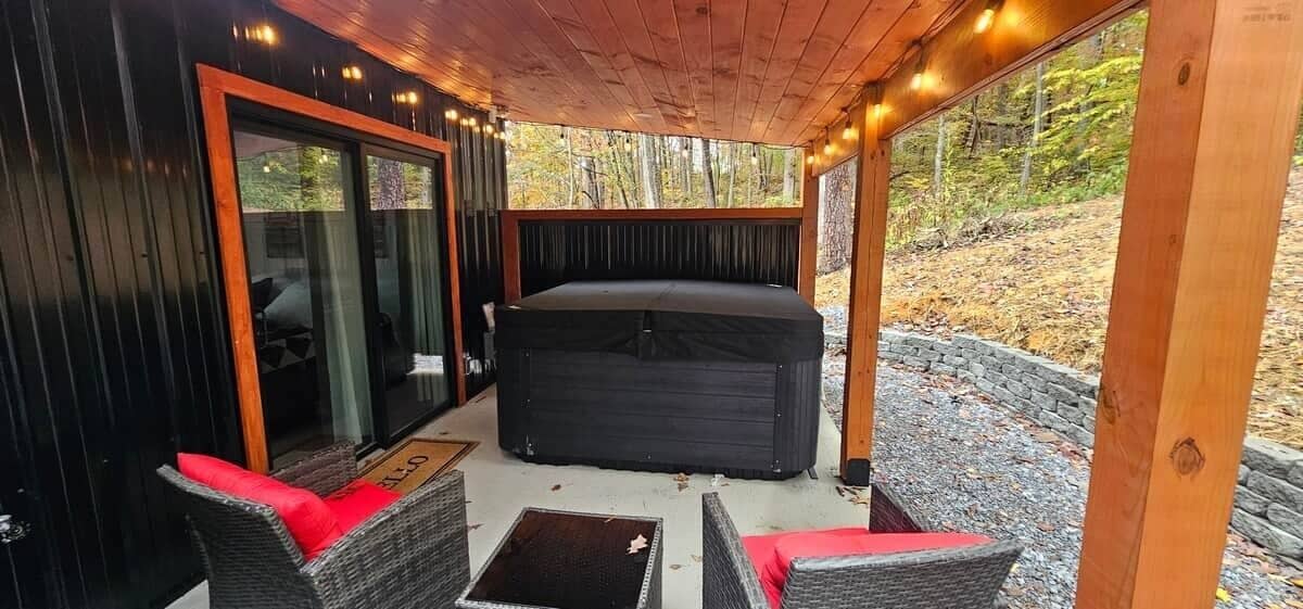 Ein überdachter Außenbereich mit Whirlpool, Korbmöbeln und einer Holzterrasse.