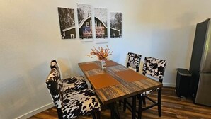 A dining area with a wooden table, cow-print chairs, and a refrigerator. - Silo Retreat (Sevierville)