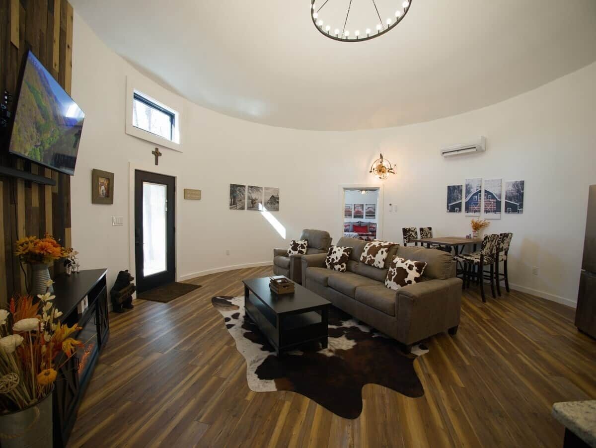 A spacious living room with a large sofa, a coffee table, and a television mounted on the wall.
