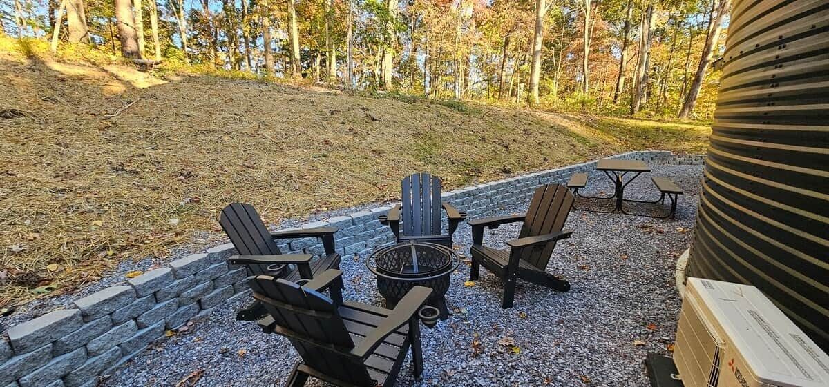 An outdoor seating area with Adirondack chairs and a fire pit.