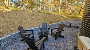 Ulkoterassi, jossa on Adirondack-tyylisiä tuoleja ja nuotiopaikka.