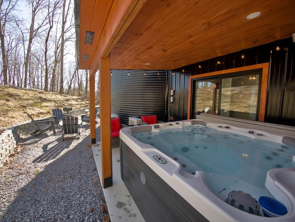 Un bain à remous avec une terrasse en bois, des sièges extérieurs et une vue sur le paysage environnant.