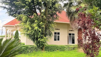 Una casa con techo rojo, un árbol grande en la fachada y un césped bien cuidado.