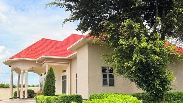 Un edificio con techo rojo, un porche cubierto y un jardín bien cuidado.