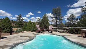 Piscina com duas cadeiras Adirondack, cercada por árvores e céu claro.