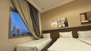 Quarto de hotel com duas camas, vista para a cidade pela janela, um relógio e obras de arte na parede.
