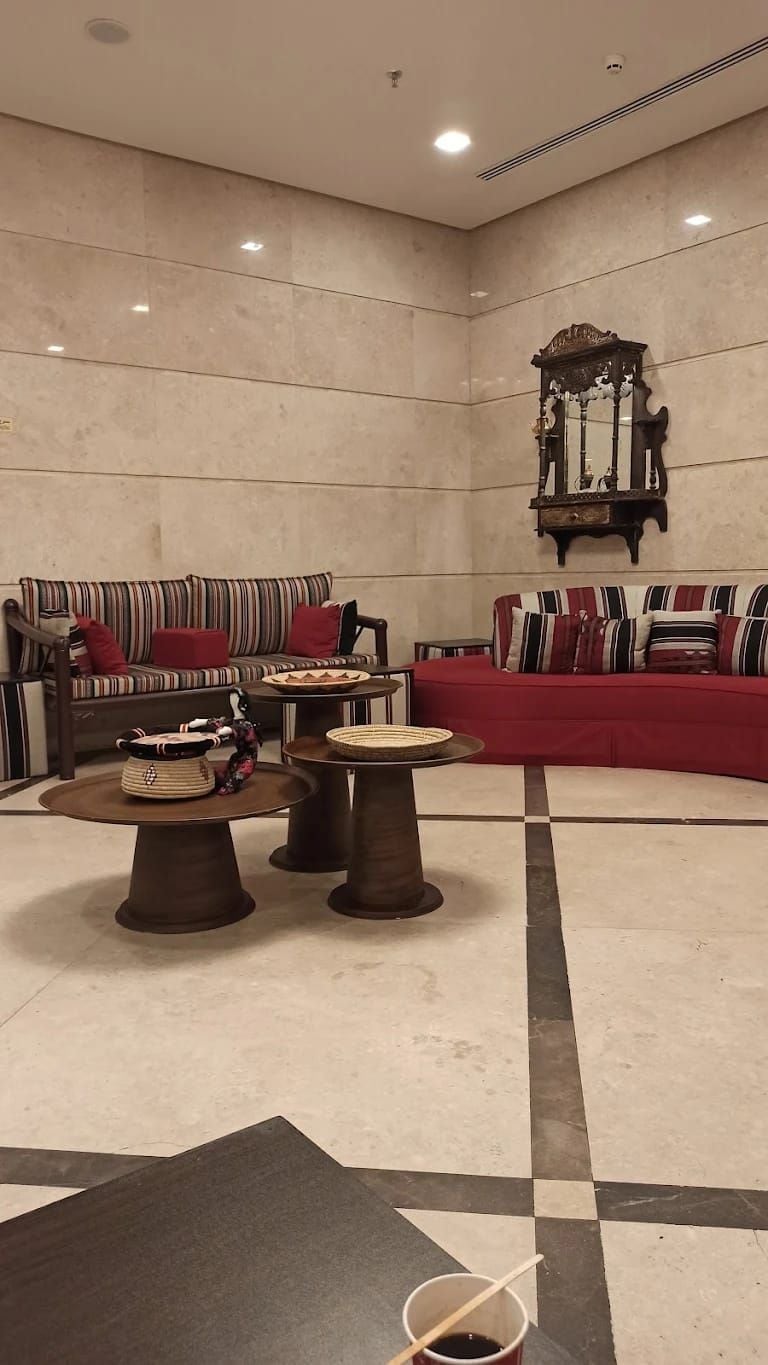 A spacious living area with a striped sofa, a round coffee table, and a decorative mirror.