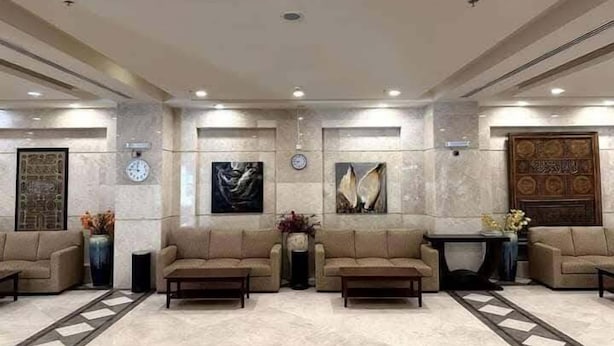 Um hall de entrada com quatro sofás, uma mesa de centro, um relógio e obras de arte nas paredes.