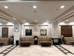 Un hall con cuatro sofás, una mesa de centro, un reloj y obras de arte en las paredes.